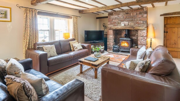 A cozy living room with a stone fireplace, leather sofas, and a television. - Dudmire (Appleby-in-Westmorland)