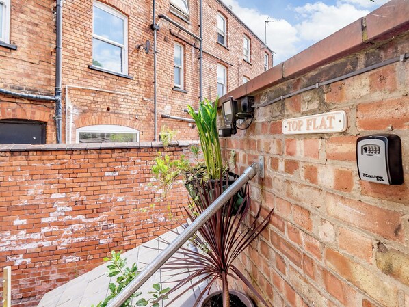 A brick building with a metal handrail, a 'TOP FLAT' sign, and a Master Lock security device.