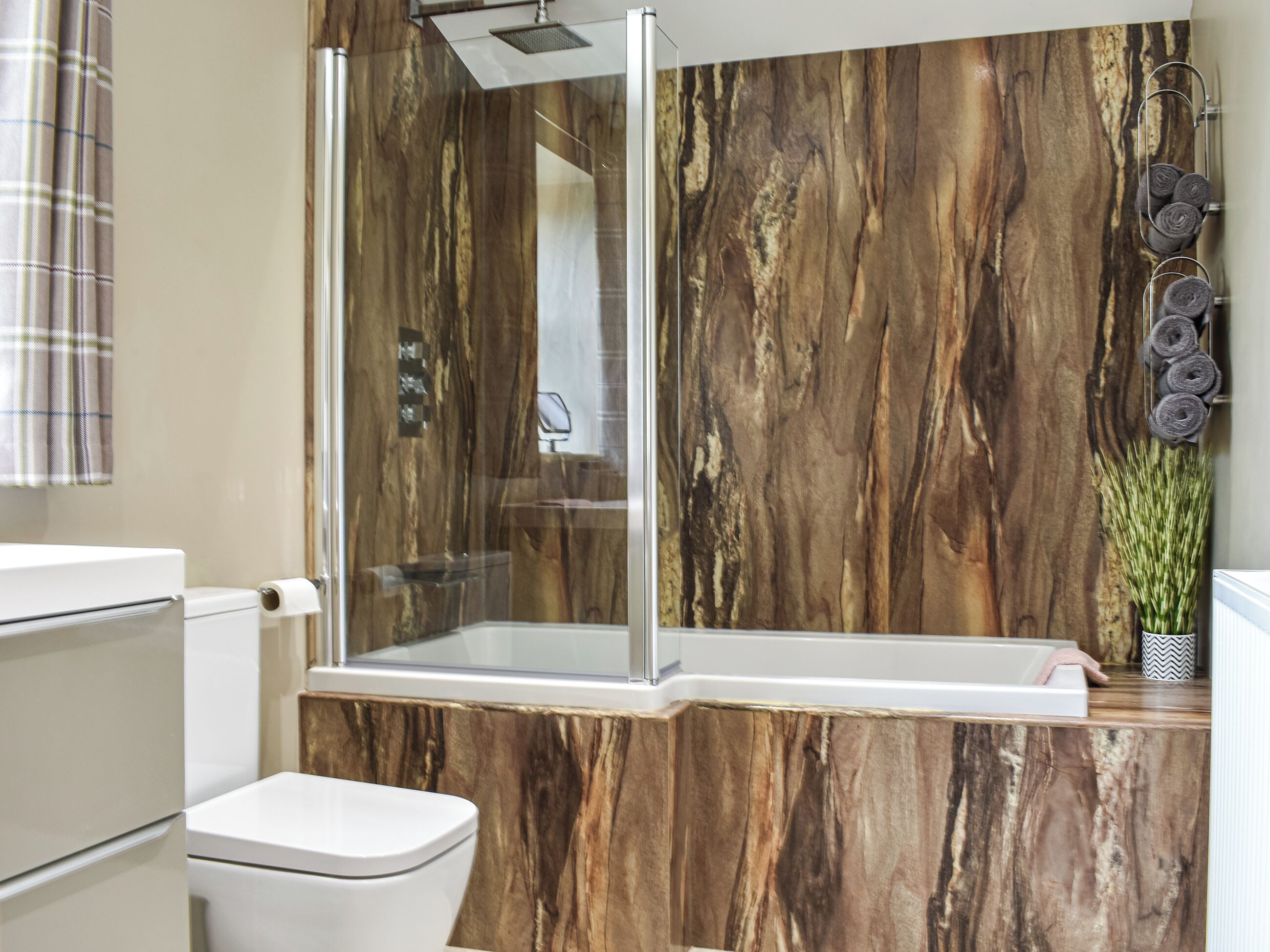 A modern bathroom with a glass-enclosed shower, a white toilet, and a marble-patterned wall.