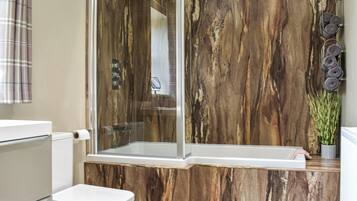 A modern bathroom with a glass-enclosed shower, a white toilet, and a marble-patterned wall.