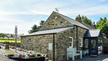 A stone building with a sloped roof, a small porch, and a gravel driveway.