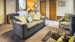 A cozy living room with a grey sofa, a patterned armchair, and a small side table. - 2 bedroom accommodation in Westgate, Near Stanhope (Westgate, Near Stanhope)