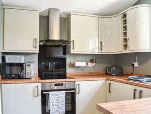 Une cuisine moderne dotée d’appareils électroménagers en acier inoxydable, de plans de travail en bois et de meubles de couleur claire.