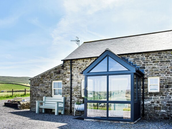 A stone building with a large glass window, a bench, and a metal fence in the background. - 2 bedroom accommodation in Westgate, Near Stanhope (Westgate, Near Stanhope)