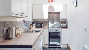 Una cocina moderna con armarios blancos, encimera de madera, microondas, tostadora y horno doble.