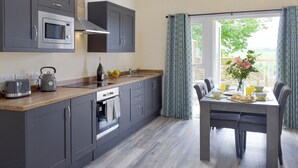 Een moderne keuken met grijze kastjes, een ingebouwde oven en een eethoek met een tafel gedekt voor twee personen.