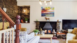 Een gezellige woonkamer met een open haard, een televisie en een trap.
