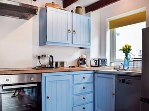 A kitchen with blue cabinets, a coffee maker, a toaster, and a dishwasher. - 4 bedroom accommodation in Pwll near Llanelli (Pwll near Llanelli)