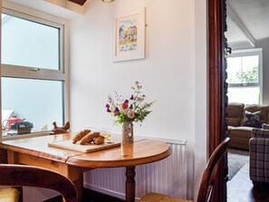 A dining area with a wooden table, a vase of flowers, and a painting on the wall.