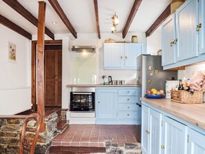 A kitchen with blue cabinets, a built-in oven, and a stone fireplace. - 4 bedroom accommodation in Pwll near Llanelli (Pwll near Llanelli)