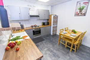 Una cocina compacta con comedor, que incluye una mesa de madera, sillas y un refrigerador.