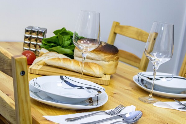 A wooden dining table with plates, cutlery, and a glass of water. - Cades Accommodation (Wolverhampton)