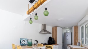 A modern kitchen with a wooden dining table, yellow chairs, and a built-in washing machine. - Seaside villa sleeps 6, garden, air conditioning, garage (La Grande-Motte)