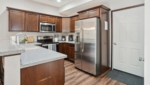 A modern kitchen with wooden cabinets, stainless steel appliances, and a granite countertop. - Spacious 4 BR Home Convenient Location (Tiffin)
