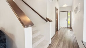 A staircase with wooden handrails and carpeted steps leading to a door. - Spacious 4 BR Home Convenient Location (Tiffin)