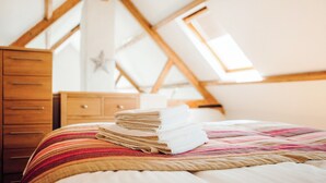 A bedroom with a bed, a stack of towels, a wooden dresser, and a star decoration on the wall.