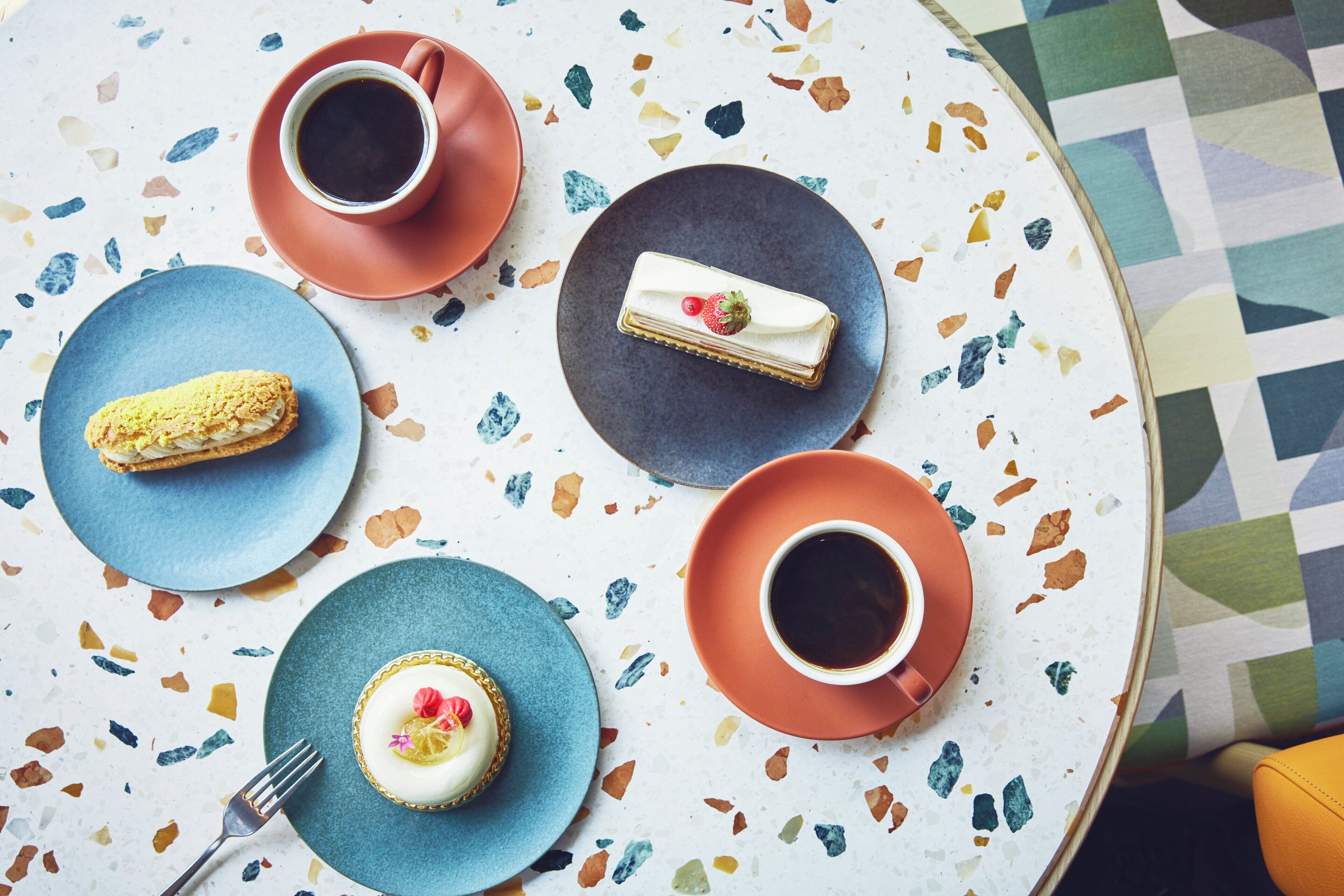 A table with a variety of desserts and coffee cups.