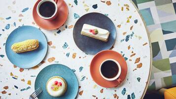 A table with a variety of desserts and coffee cups.