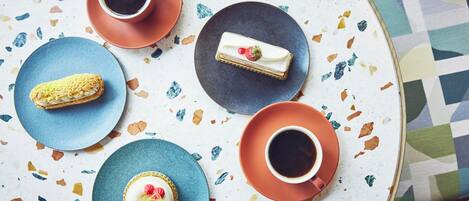 A table with a variety of desserts and coffee cups.