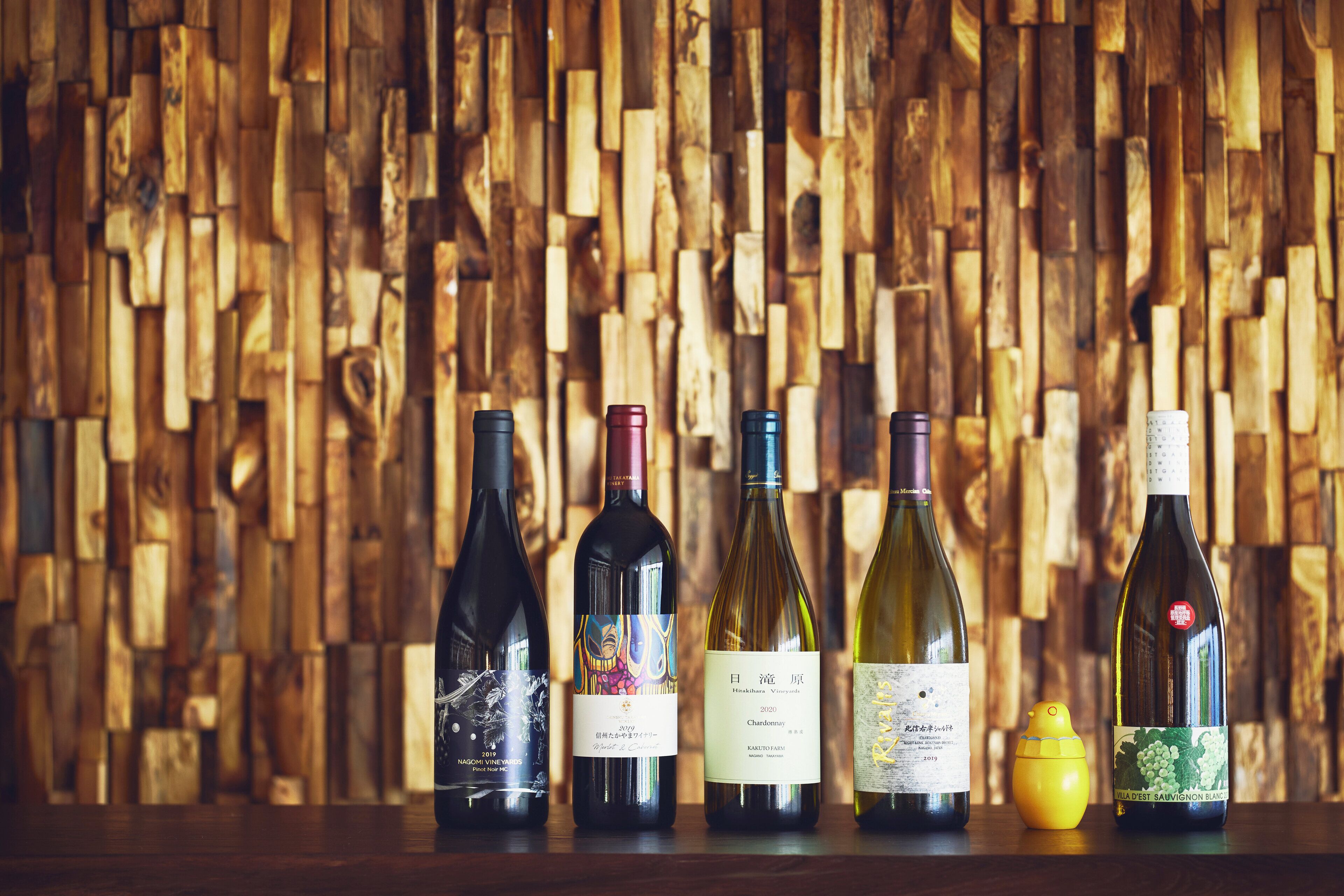 Varias botellas de vino sobre una superficie de madera, con un fondo de pared de madera.