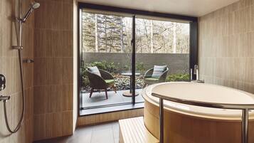 A modern bathroom with a bathtub, shower, and seating area with chairs and a table.
