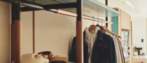 A clothing rack with various garments, a pair of shoes, and a small table with a cup and a bag.