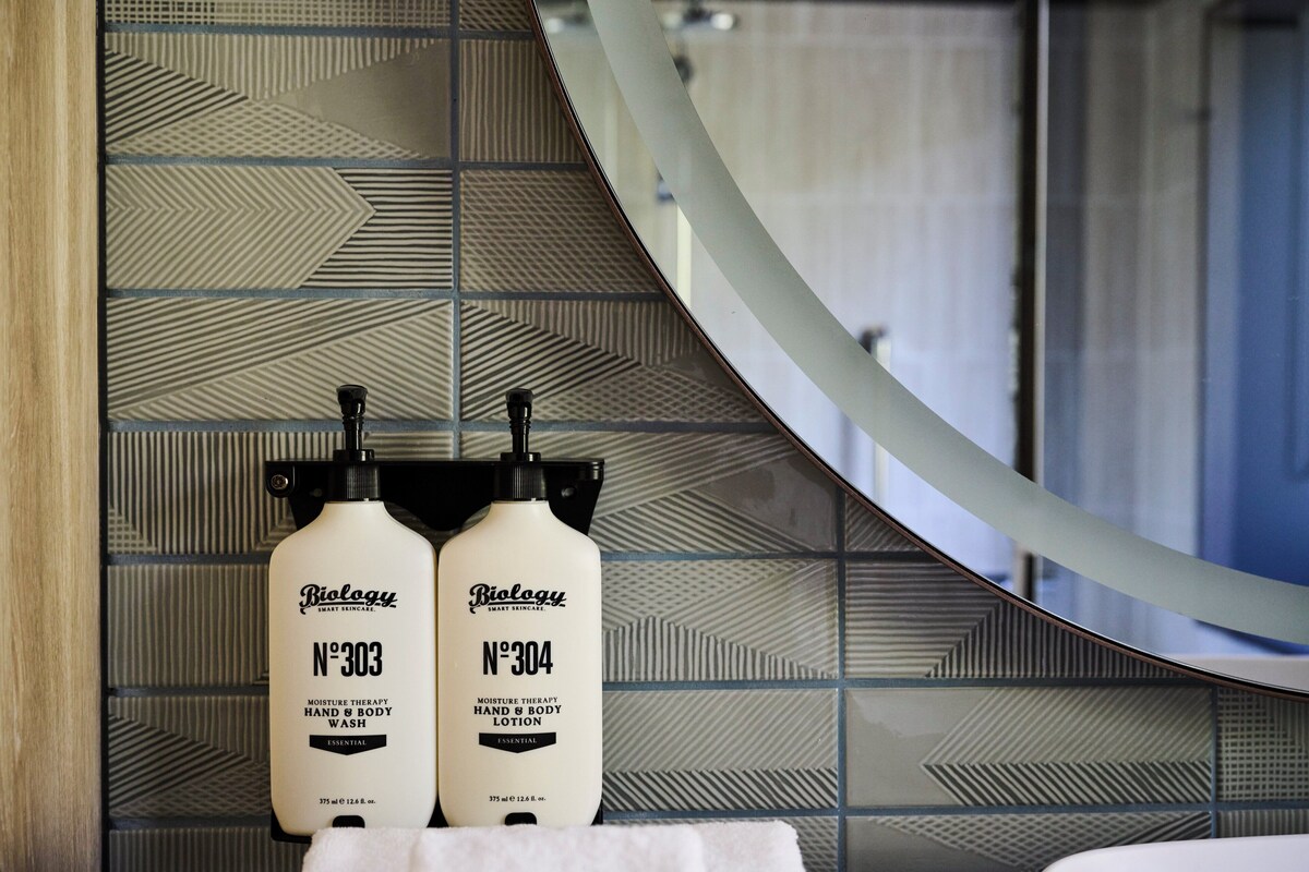 Dos botellas de jabón líquido Biolgy N-303 para manos y cuerpo sobre una encimera de baño.