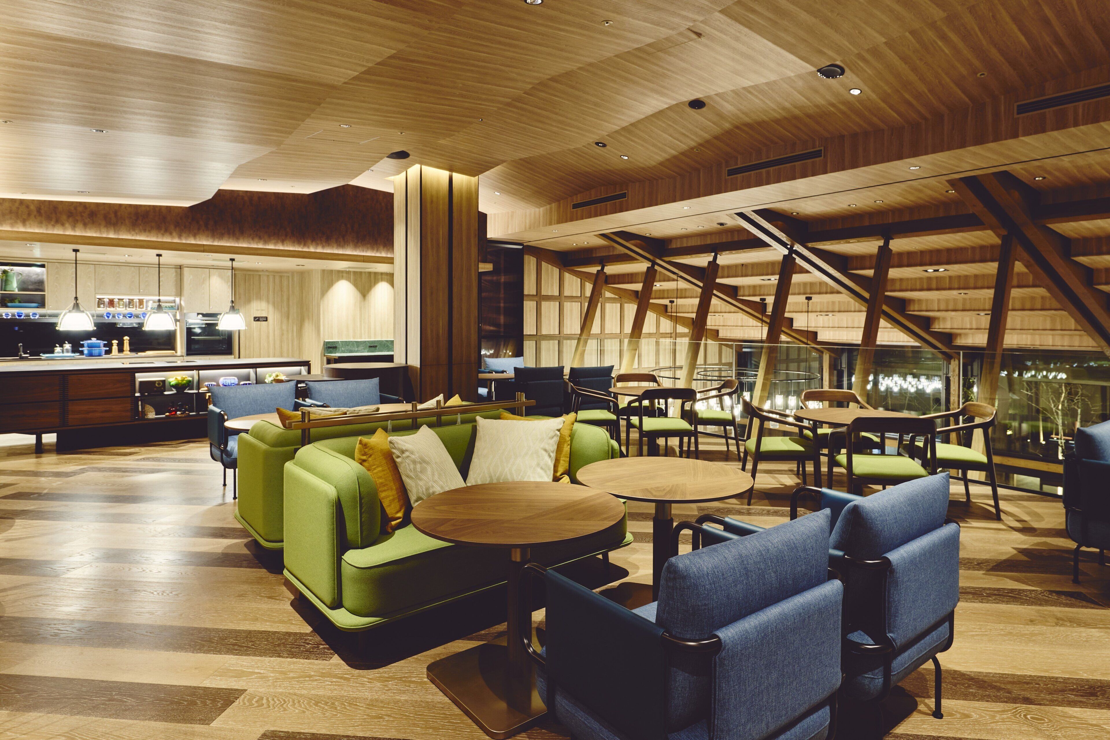 A modern interior with green sofas, blue chairs, and wooden tables.
