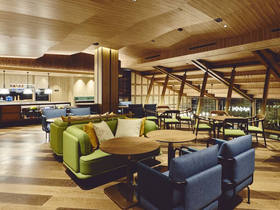 A modern interior with green sofas, blue chairs, and wooden tables.