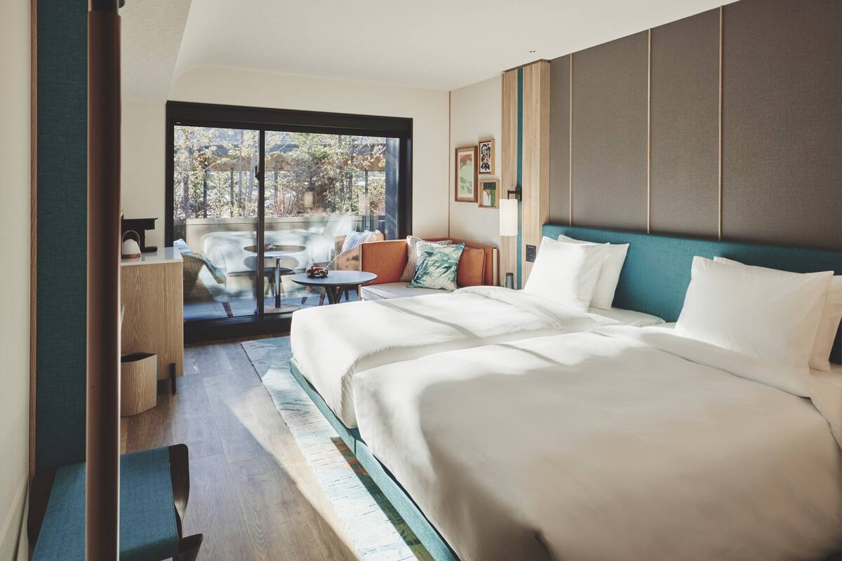 A hotel room with a large bed, a seating area with a table, and a view of the outdoors.