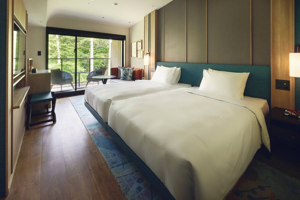 A hotel room with two large beds, a desk, and a chair.