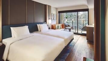 A hotel room with two beds, a small table, and a view of the outdoors.