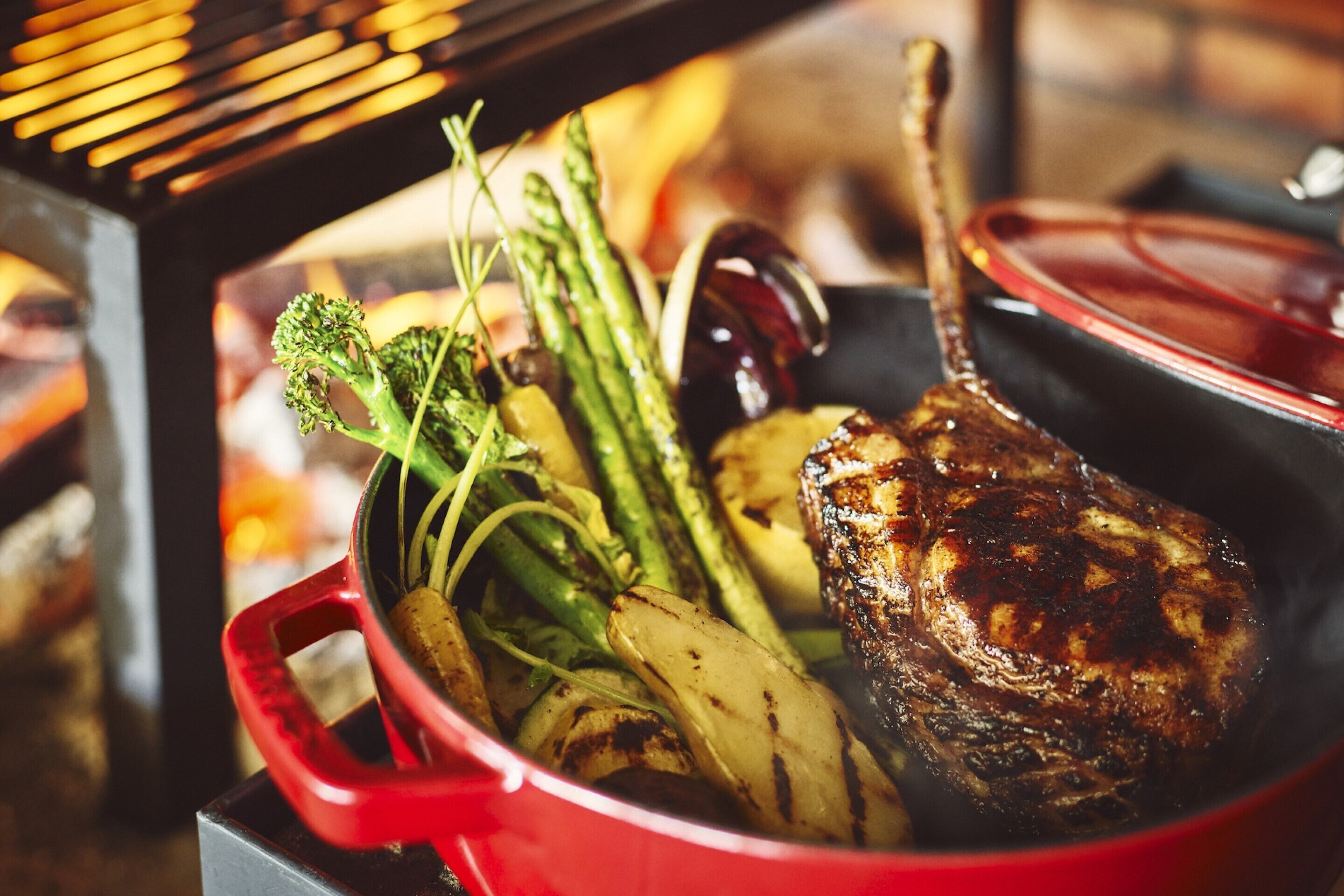A red pot with a roast and vegetables inside.