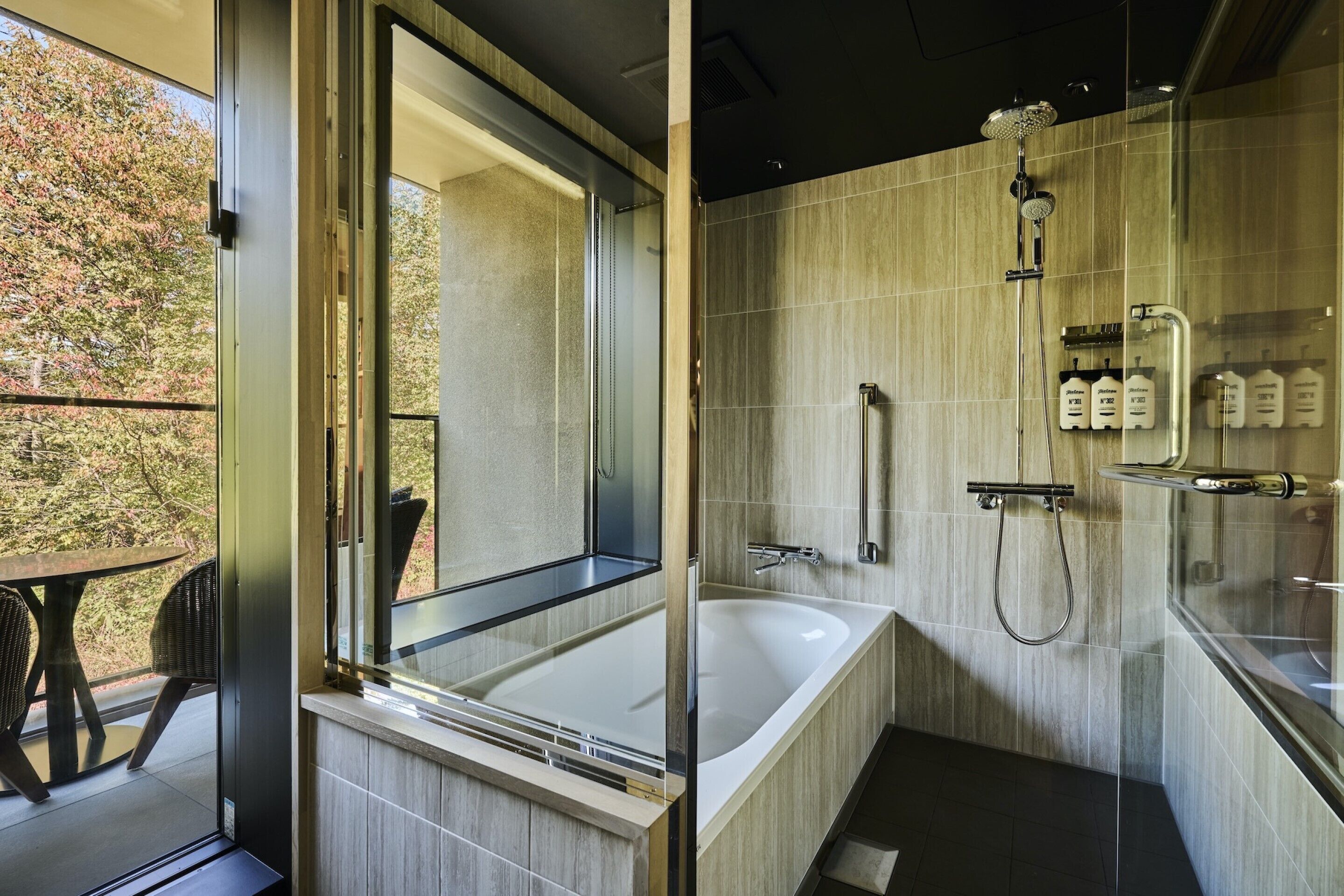 A modern bathroom with a large bathtub, a glass-enclosed shower area, and a view of the outdoors.