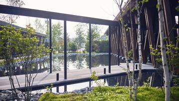Un espace extérieur moderne doté d’une terrasse en bois, d’un étang et d’un pont.
