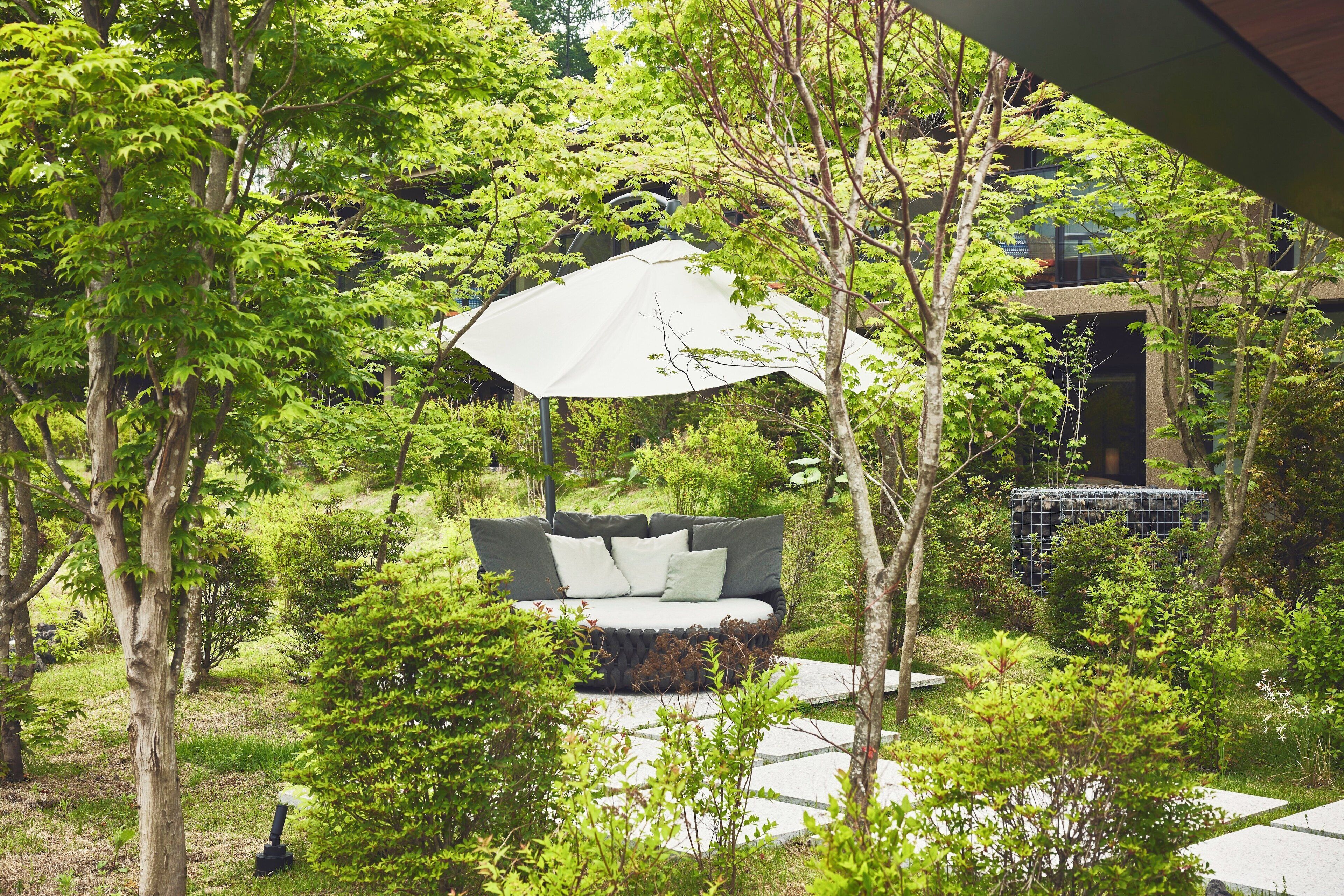 A garden with a large outdoor sofa and a white umbrella.