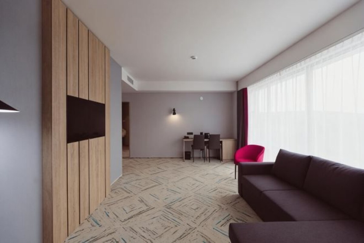 Un salon moderne avec un canapé, un coin repas avec des chaises et une grande fenêtre.