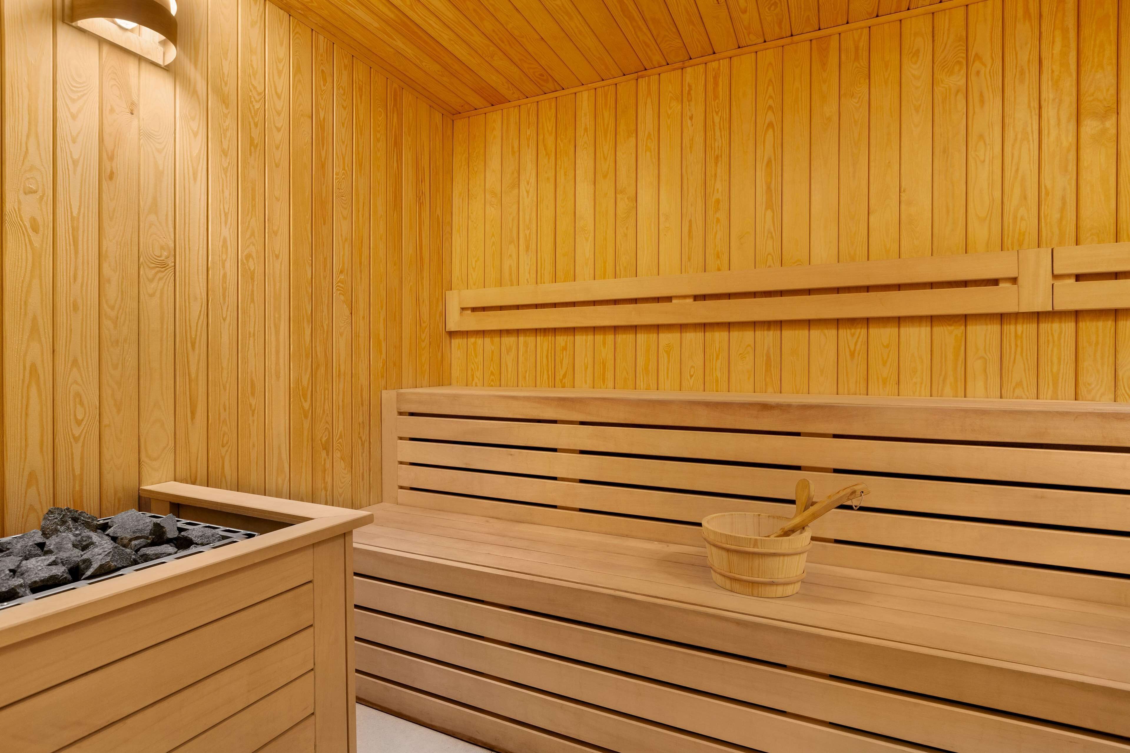 Una sauna de madera con bancos y un calentador de piedra.