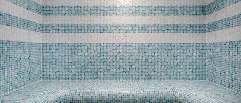 Una habitación con paredes y suelo de azulejos, y un banco curvo.