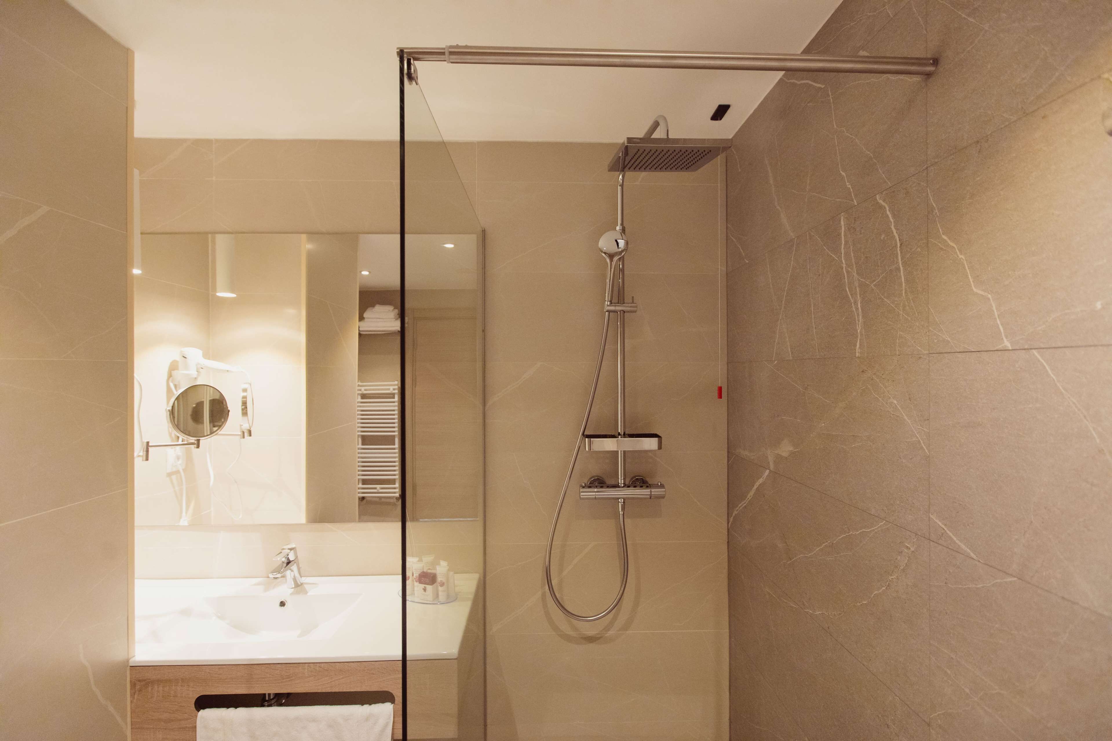 A modern bathroom with a glass-enclosed shower, a sink, and a mirror.