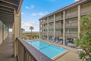 A hotel with a pool, outdoor seating, and a view of the beach.