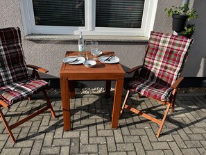 A wooden table with two plaid chairs, a bottle, and plates set for two. - Paula Vacation Apartment (Senftenberg)