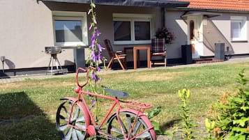 A red bicycle parked in a grassy yard with a house in the background.