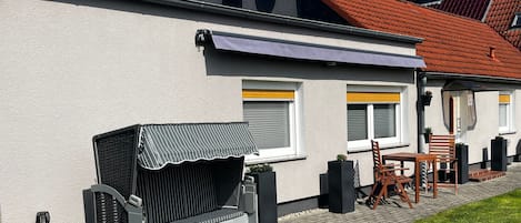 Una casa con un patio que incluye una parrilla, asientos al aire libre y un pequeño jardín.