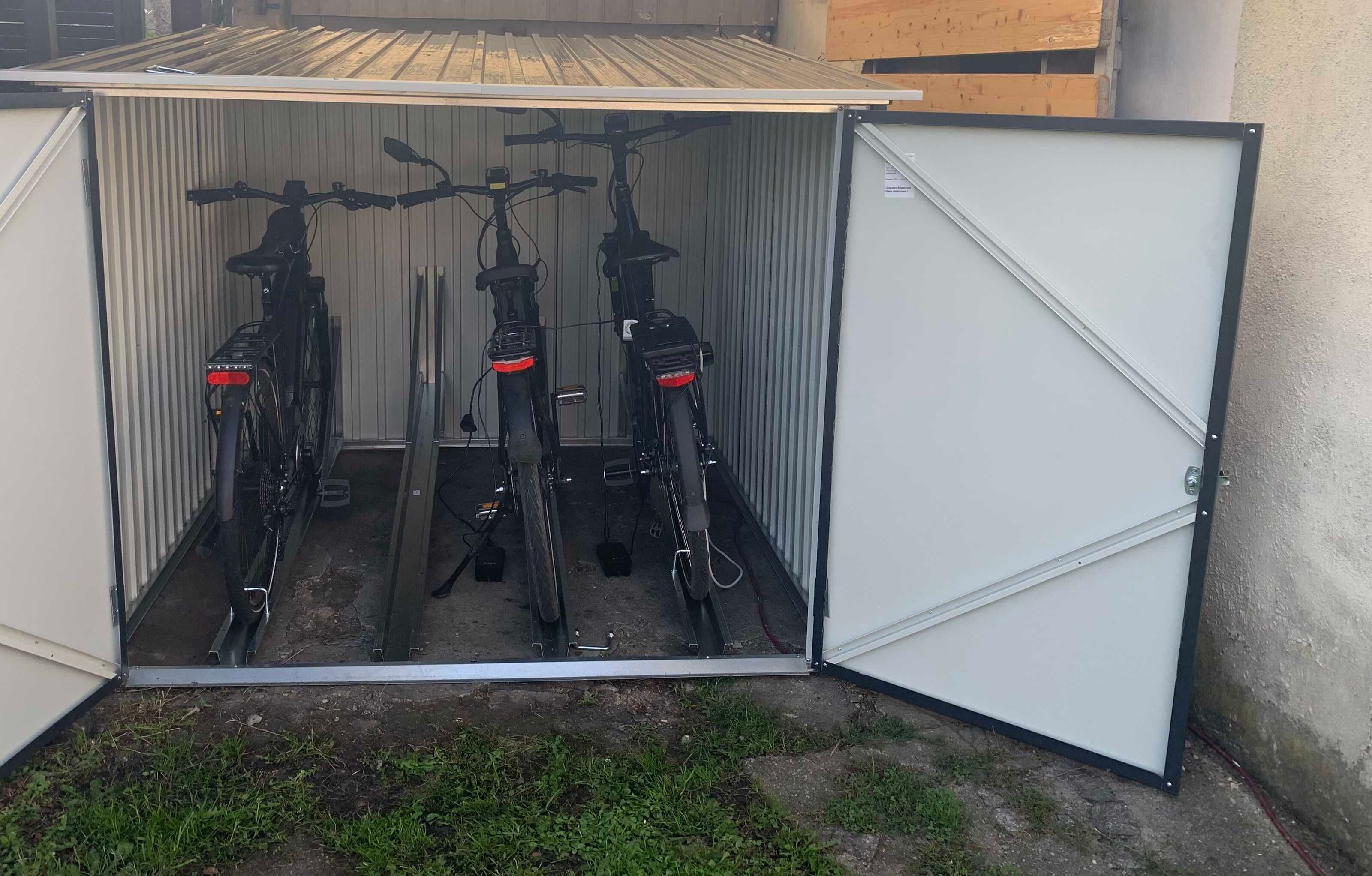 A metal shed with a hinged door, containing two bicycles inside.