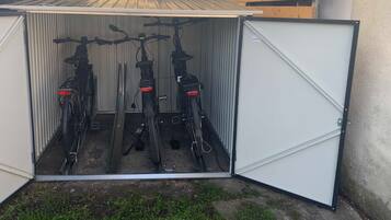 A metal shed with a hinged door, containing two bicycles inside.