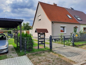 A residential house with a red-tiled roof, a covered porch, and a fenced yard. - Vacation apartment Paula (Senftenberg)