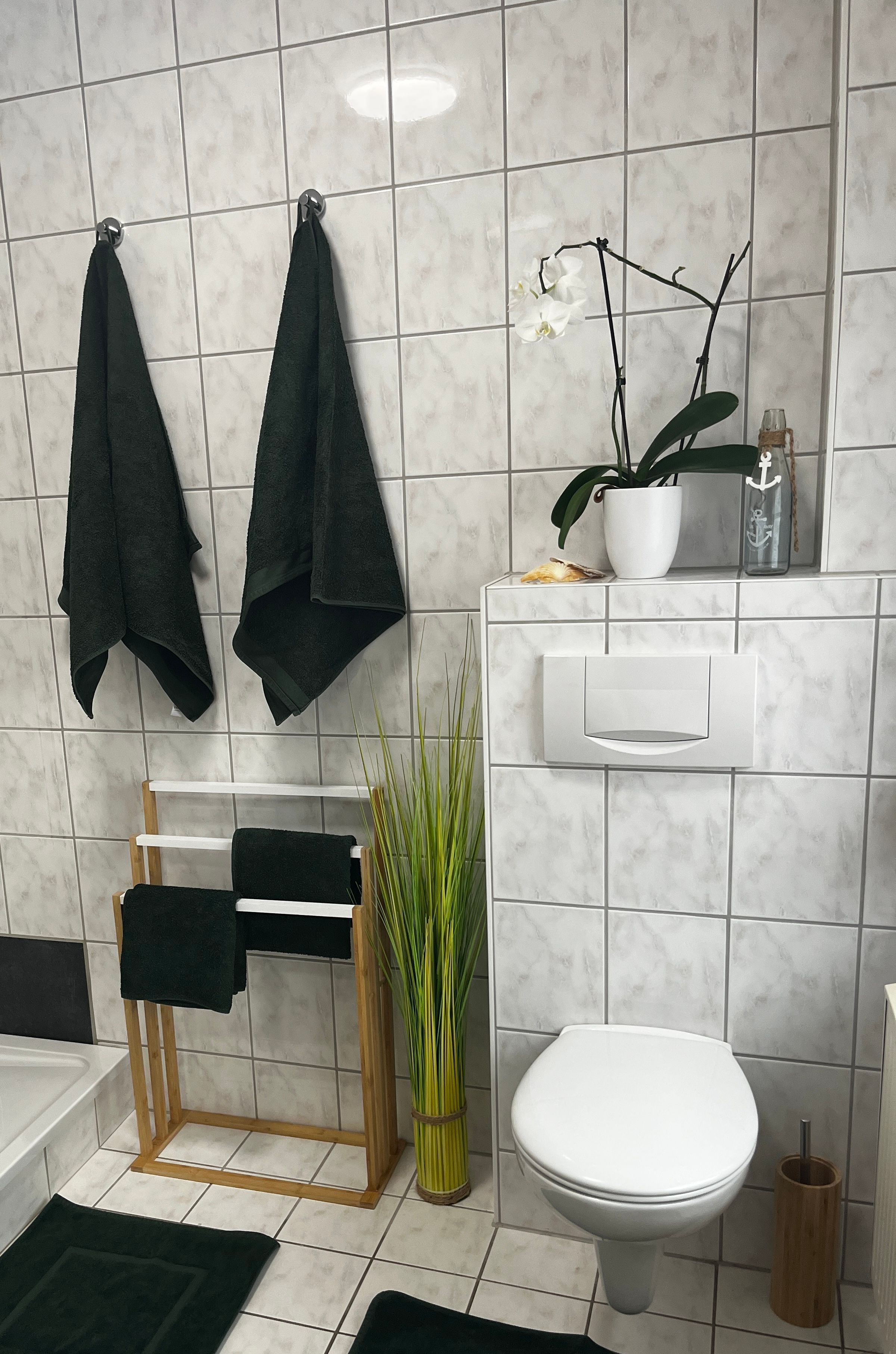 Un baño con inodoro, lavamanos y un perchero con dos toallas.