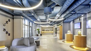 A modern lobby with seating areas, a reception desk, and a large window providing natural light. - Sunday Hotel Düsseldorf Seestern (Düsseldorf)