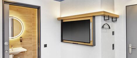 Un baño moderno con tocador de madera, un espejo grande y una televisión integrada.